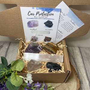 Peut inclure: Une boîte en carton marron contenant un kit de cristaux bruts pour la protection de la voiture. La boîte contient des cristaux d'améthyste, de sélénite, de tourmaline, d'œil de tigre et de quartz clair. La boîte est étiquetée "Car Protection Raw Crystal Kit".