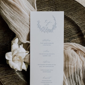 Può includere: Un menu bianco con un design floreale blu e testo in calligrafia. Il menu include antipasti, contorni, piatti principali e dessert. Il testo recita: "starters", "Fresh vegetable spring rolls", "cordon blue bites", "sides", "Crab and corn soup asian stir fry", "vegetables salad", "entrees", "Beef tenderloin with shitake red wine gravy, slow roasted pork belly", "Grilled norwegian salmon with dill mustard", "dessert", "Assorted petit fours", "Chocolate ganache cake", "Fresh fruits".