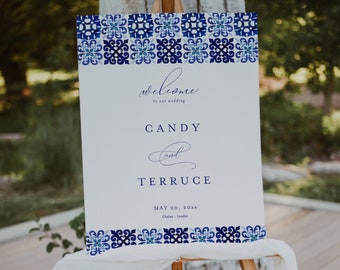 Op de afbeelding: Een wit welkomstschild voor een bruiloft met een blauwe en witte tegelmotiefrand. Het bord staat: "Welkom op onze bruiloft Candy en Terruce 20 mei 20XX Charleston - Londen"