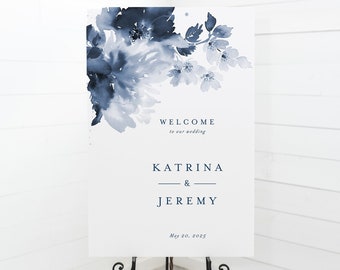 May include: A white wedding welcome sign with a blue watercolor floral design. The sign reads "Welcome to our wedding, Katrina & Jeremy, May 20, 2025".