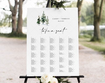 May include: A white wedding seating chart with a watercolor illustration of pine trees at the top. The chart is on an easel and has the text "Candy + Terruce" and "May 28, 2021" at the top. The text "Take a seat" is written in cursive below the trees. The chart lists guest names and table assignments.