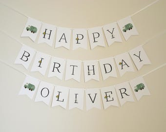 May include: White banner with green garbage trucks and the text "Happy Birthday Oliver" in black.