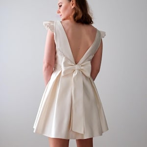 Short wedding dress with plunging back and elegant bow – Modern and refined style for a unique civil wedding. Chic and modern in satin