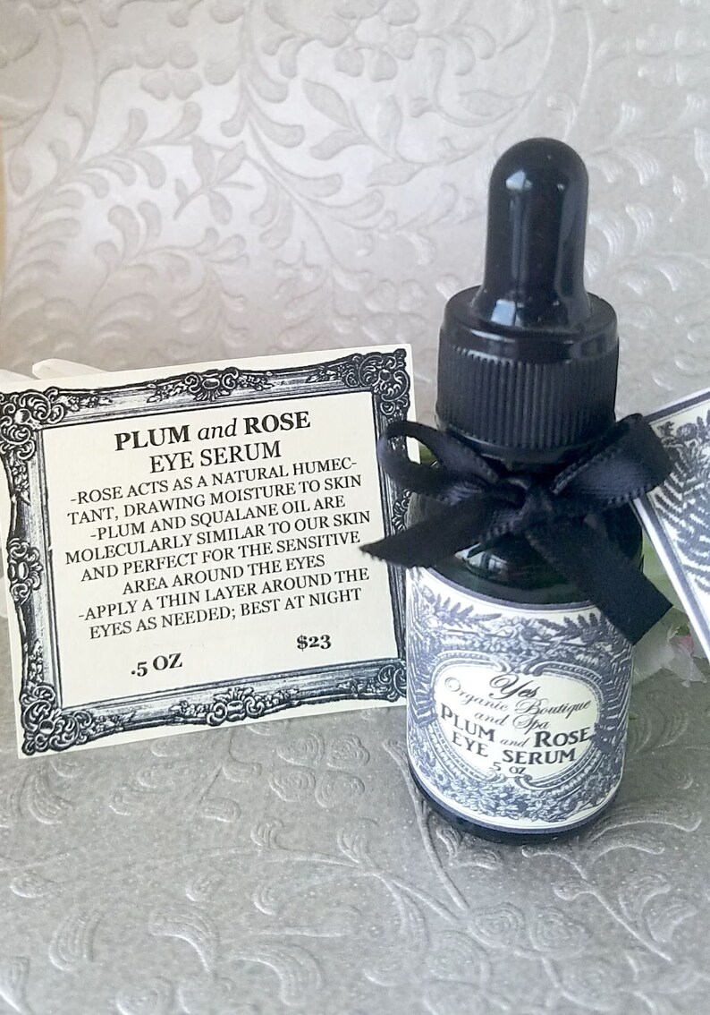 Pode incluir: Uma pequena garrafa de vidro de s&eacute;rum para os olhos Plum and Rose com conta-gotas preto e la&ccedil;o preto. Um cart&atilde;o com o nome e a descri&ccedil;&atilde;o do produto est&aacute; ao lado da garrafa. O r&oacute;tulo diz "Yes Organic Boutique and Spa".