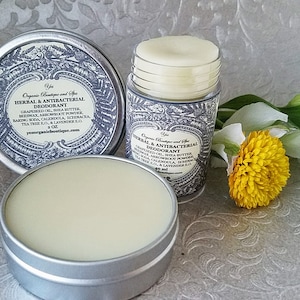 May include: Two containers of natural herbal and antibacterial deodorant. The deodorant is in a silver tin and a white plastic tube. The label on the tin is black and white with a floral design and the text "Yes Organic Boutique and Spa Herbal & Antibacterial Deodorant Grape seed oil, Shea butter, Beeswax, Arrowroot powder, Baking soda, Calendula, Echinacea, Tea tree EO, & Lavender EO 2 oz yesorganicboutique.com". The label on the tube is similar but smaller and says "Yes Organic Boutique and Spa Herbal & Antibacterial Deodorant Grape seed oil, Shea butter, Beeswax, Arrowroot powder, Baking soda, Calendula, Echinacea, Tea tree EO, & Lavender EO 40 ml yesorganicboutique.com".