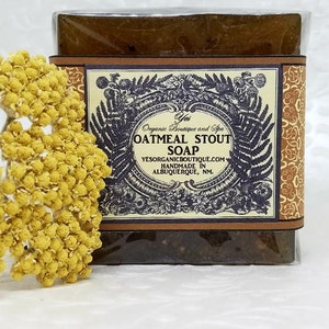 Puede incluir: Una barra de jabón marrón de avena y cerveza negra con una etiqueta decorativa que dice "Yes Organic Boutique and Spa Oatmeal Stout Soap Yesorganicboutique.com Handmade in Albuquerque, NM."