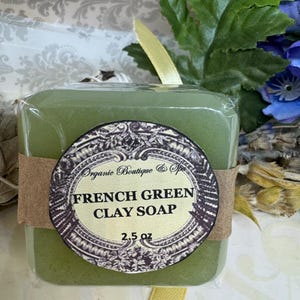 May include: A green bar of soap with a brown label that reads "Organic Boutique & Spa French Green Clay Soap 2.5 oz".