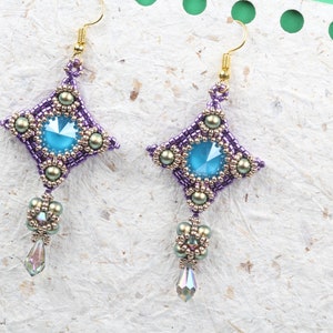 May include: A pair of purple and gold beaded earrings with a blue crystal centerpiece and a teardrop crystal dangle.