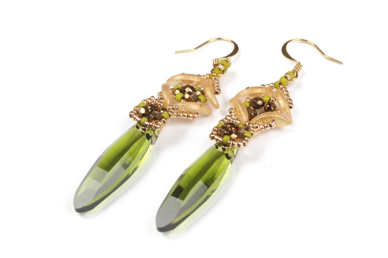 May include: A pair of green and gold dangle earrings with a geometric design. The earrings feature a teardrop-shaped green crystal and gold beads.