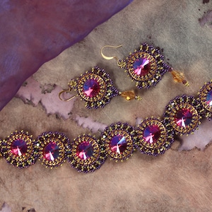 Puede incluir: Un conjunto de joyas de cuentas moradas y doradas con acentos de cristal rosa iridiscente. El conjunto incluye un brazalete y un par de pendientes.