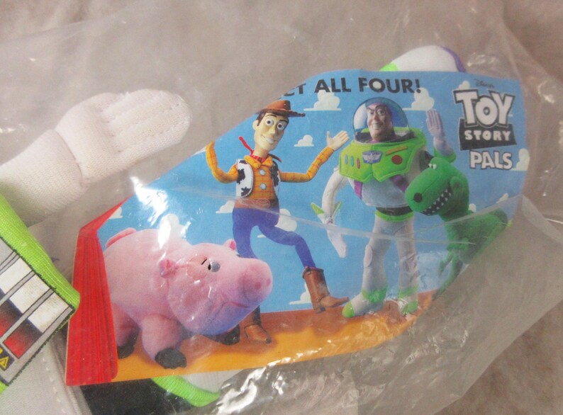 K&ouml;nnte beinhalten: Ein Toy Story Pals Spielzeugset mit den Charakteren Woody, Buzz Lightyear, Hamm und Rex. Die Verpackung ist blau mit den Worten "LET ALL FOUR!" und "Toy Story Pals". Das Spielzeug befindet sich in einer transparenten Plastikt&uuml;te.