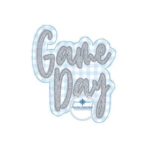 May include: Silver glitter "Game Day" text on a blue and white gingham background. The text is outlined in black. A small logo for "Just Sew Embroidery" is in the lower right corner.