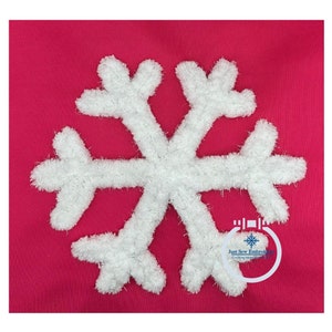 Op de afbeelding: Een witte sneeuwvlok met een pluche textuur is geborduurd op een felroze stof. De sneeuwvlok is gecentreerd in de afbeelding en is het enige zichtbare element. De tekst "Just Sew Embroidery" is zichtbaar in de rechterbenedenhoek van de afbeelding.