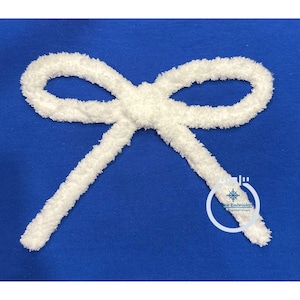 Op de afbeelding: Een witte, pluche strik op een koninklijk blauwe achtergrond. De strik is gemaakt van een zacht, pluche materiaal en is in een eenvoudige knoop geknoopt. De strik is een decoratief element dat voor verschillende doeleinden kan worden gebruikt, zoals het toevoegen van een vleugje whimsy aan een knutselproject of het creëren van een feestelijke sfeer voor een speciale gelegenheid.