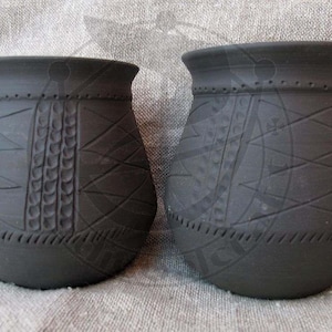 Peut inclure: Deux tasses en céramique noire avec des motifs géométriques complexes. Les tasses ont une forme arrondie et une surface texturée.