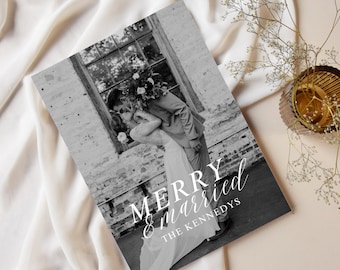 May include: Black and white wedding photo print featuring a couple kissing in front of a brick wall. The text "MERRY & married THE KENNEDYS" is written in white script. The print is displayed on a cream-colored fabric.