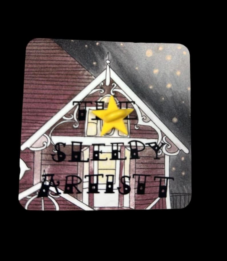 May include: A square sticker with a detailed illustration of a house. The house has a burgundy roof and white trim. The text "THE SLEEPY ARTIST" is displayed on the house. A yellow star is affixed to the top. The background is a night sky.