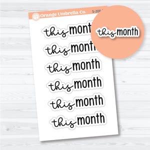 May include: A sheet of white stickers with the text "this month" in a black, handwritten-style font. The stickers are arranged in rows. A peach-colored circle with a single sticker is in the upper right corner.