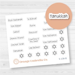 May include: A sheet of white stickers with various Jewish holiday names in black text, including "Hanukkah", "Rosh Hashanah", and "Passover". A round sticker with "Hanukkah" is also present. The stickers feature Star of David symbols.