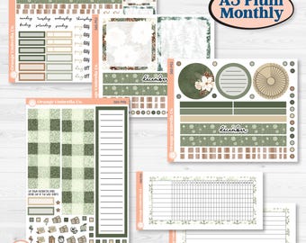 Op de afbeelding: Een collectie A5 Plum Monthly planner-stickervellen van Orange Umbrella Co. in groen-, beige- en wittinten met bloemen-, dennen- en ruitpatronen. Bevat datumkoppen, checklists, trackers en diverse kleine iconen.