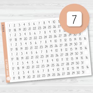 May include: A sheet of calendar number stickers with the numbers 1-31. A round sticker with the number 7 is in the upper right corner. The stickers are white with black numbers and are arranged in rows and columns.