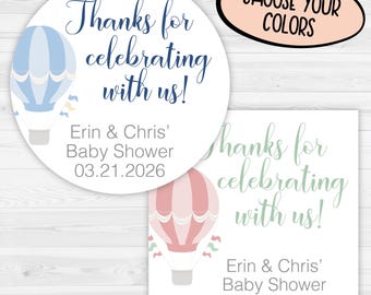 May include: Two baby shower favor stickers. One is round with a blue hot air balloon and the text "Thanks for celebrating with us!" The other is square with a pink hot air balloon and the same text. The stickers include the names "Erin & Chris" and the date.