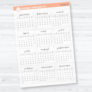 Op de afbeelding: Een witte papieren kalender met maandelijkse kalenderindelingen in handschrift. Elke maand is benoemd. Het logo van Orange Umbrella Co. staat linksboven. Afmetingen in centimeters.