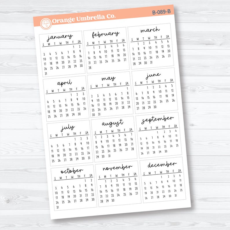 Op de afbeelding: Een vel witte kalenderstickers met de maanden van het jaar. Elke maand wordt weergegeven in een apart vak met de dagen van de week en de datums in zwarte letters. Het logo van Orange Umbrella Co. staat linksboven. Code B-089-B.