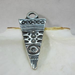 May include: A silver triangular pendant with an intricate geometric design. The pendant has a loop at the top for attaching to a chain or cord.
