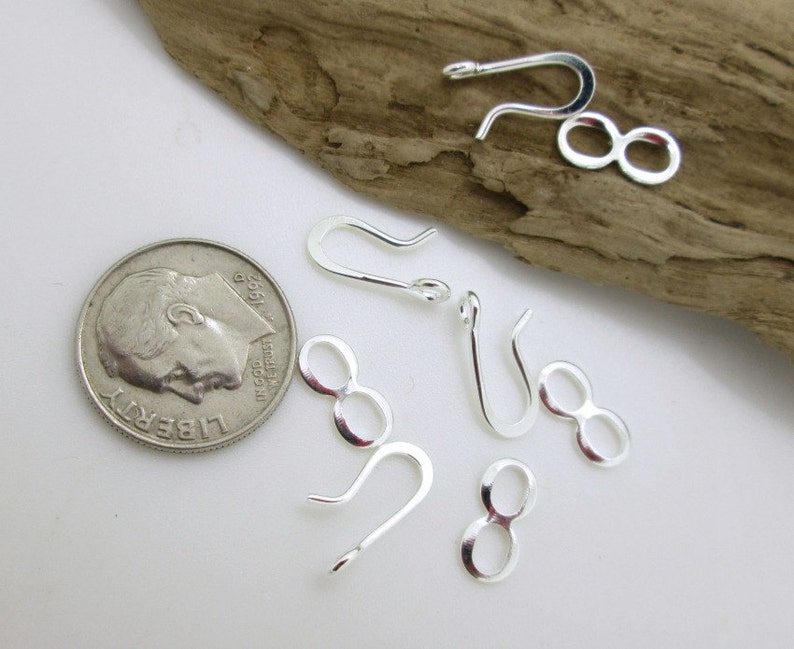May include: Silver-toned jewelry findings, including a set of 5 jump rings and 5 lobster claw clasps. The findings are shown next to a US dime for scale.