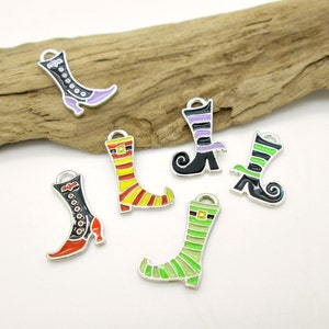 May include: Six silver witch boot charms with different colored stripes and designs. The charms are on a wooden surface.
