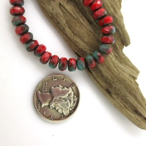 May include: A strand of faceted beads in red and teal hues. The beads are displayed next to a silver coin from 1940 and a piece of driftwood. The beads are approximately 0.25 inches in diameter.