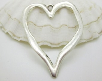May include: A silver-colored heart-shaped pendant with a textured surface. The pendant has a small loop at the top for hanging and is set against a white background.