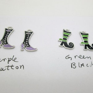 May include: Two pairs of witch boot charms. One pair is black with purple accents and the other pair is black with green accents. The charms are labeled "Purple Button" and "Green Black".