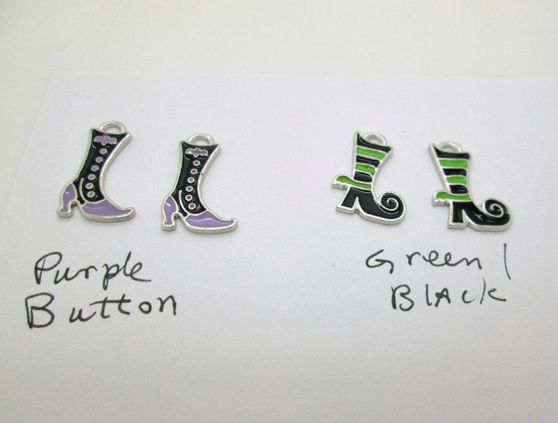 May include: Two pairs of witch boot charms. One pair is black with purple accents and the other pair is black with green accents. The charms are labeled "Purple Button" and "Green Black".