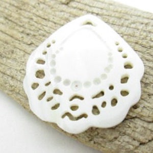 May include: White shell pendant with a delicate, intricate cutout design. The shell is shaped like a teardrop with a rounded top and a pointed bottom. The cutout design features a series of small circles and curves.