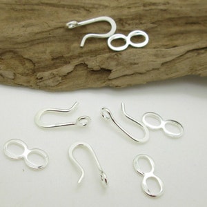 May include: Silver-toned metal jewelry findings, including a set of four lobster claw clasps and four figure-eight clasps.