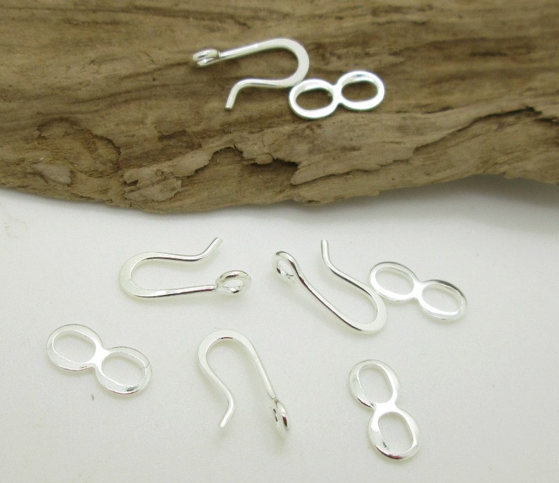 May include: Silver-toned metal jewelry findings, including a set of four lobster claw clasps and four figure-eight clasps.