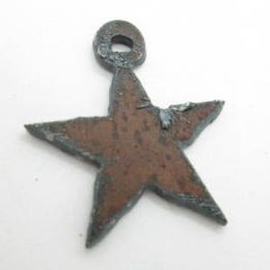 May include: A rustic, hand-crafted metal star charm with a loop at the top. The star is a deep rusty brown color with a blue patina.