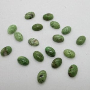 May include: A collection of 18 oval-shaped green gemstone cabochons. The stones have a mottled green and white pattern.