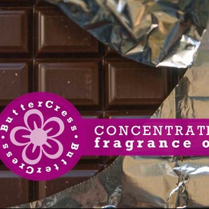 May include: A close-up of a chocolate bar with a purple sticker that says "ButterCress. ButterCress." and has a pink flower design. The sticker also says "CONCENTRATED fragrance oil".