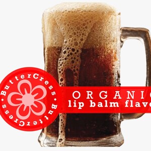 May include: A glass mug filled with a dark brown liquid with a thick head of foam. The mug has a handle. A red and white sticker with the text "ButterCress.ButterCress" and a pink flower graphic is on the left side of the image. A red banner with the text "ORGANIC lip balm flavor" is on the right side of the image.