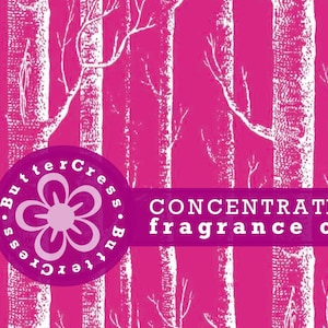 Könnte beinhalten: Ein rosa Hintergrund mit einem weißen Baummuster. Ein weißer Kreis mit einer rosa Blume und dem Text "ButterCress.ButterCress" befindet sich in der linken unteren Ecke. Ein weißes Banner mit dem Text "CONCENTRATED fragrance oil" befindet sich in der unteren Mitte.