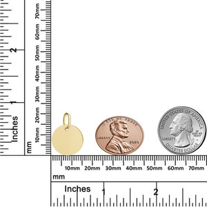Puede incluir: Un colgante redondo dorado con un peque&ntilde;o lazo para una cadena. El colgante se muestra junto a un centavo y un cuarto de d&oacute;lar para comparar el tama&ntilde;o. Medidas en pulgadas y mil&iacute;metros.