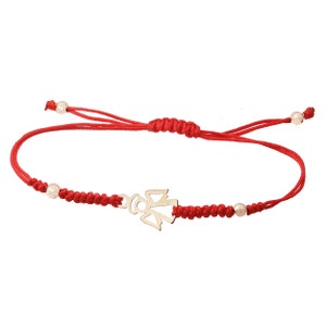 Könnte beinhalten: Rotes Armband mit einem goldenen Engelsanhänger und weißen Perlen.