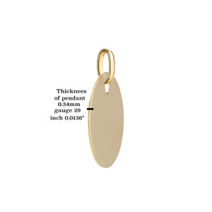 Puede incluir: Un colgante ovalado de color dorado con un peque&ntilde;o lazo en la parte superior para una cadena. El grosor del colgante es de 0,34 mm y el calibre es 29. El texto de la imagen dice: Grosor del colgante 0,34 mm calibre 29 pulgada 0,0136".