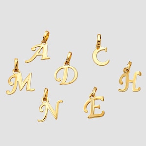 May include: A collection of six gold-toned metal letter pendants featuring the uppercase letters A, C, D, E, H, M, and N. Each individual letter charm includes a small attached jump ring at the top, designed for attachment to a necklace or bracelet chain.