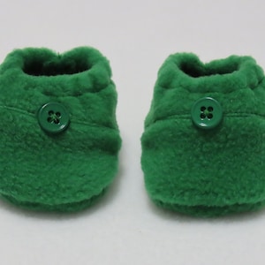 Peut inclure: Une paire de chaussons pour bébé en polaire verte avec un bouton vert sur chaque.