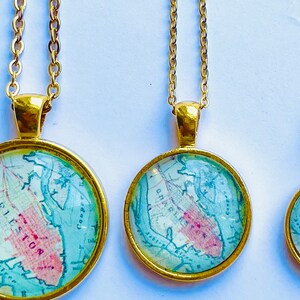 May include: Three gold necklaces with round glass pendants featuring a vintage map of a city. The pendants are different sizes.