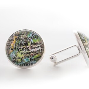 May include: A pair of silver cufflinks with a map of New York City on the front. The map shows the boroughs of Manhattan, Brooklyn, Queens, the Bronx, and Staten Island. The cufflinks are a great way to show your love for the city.